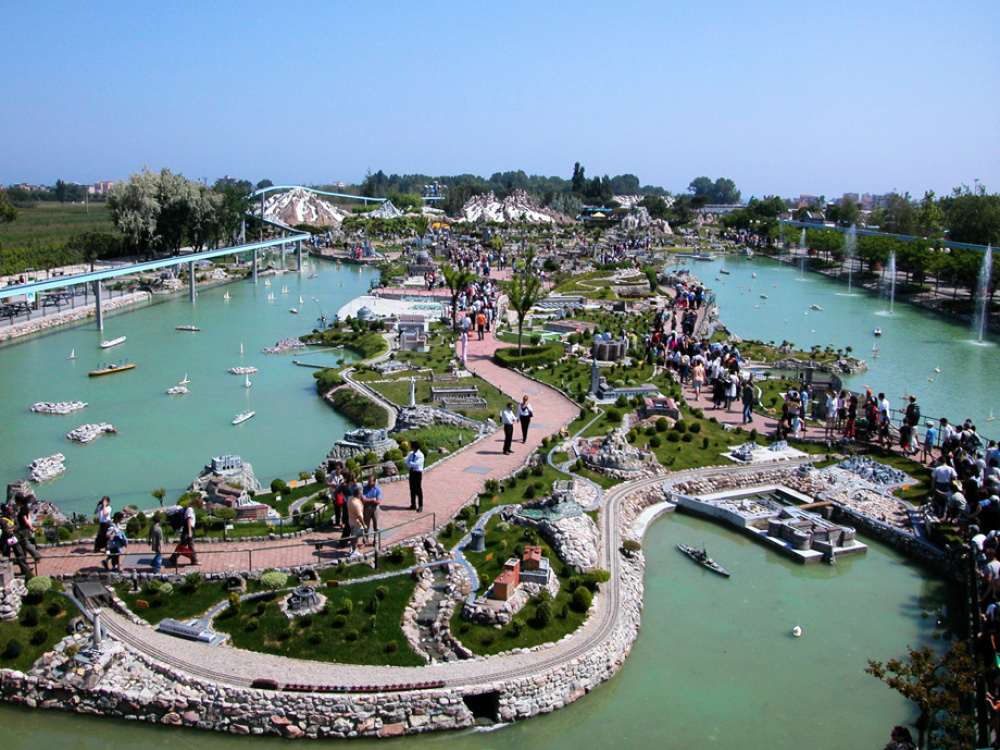 Parco in miniatura con modellini di edifici e folla di visitatori.