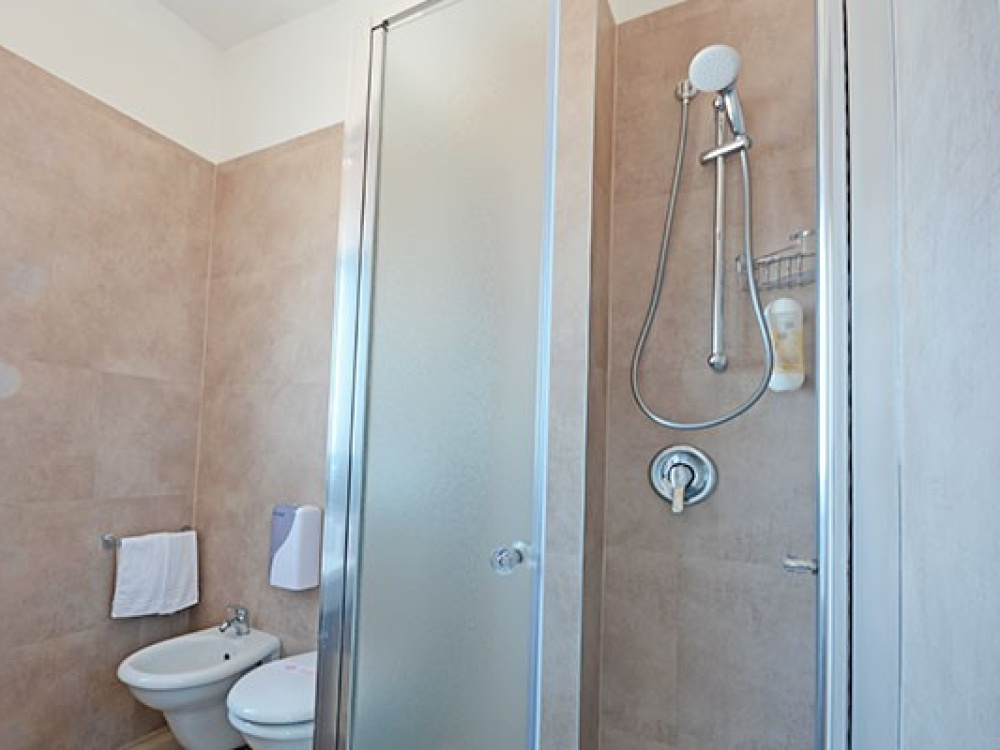 Bagno moderno con doccia, bidet e lavabo, piastrelle beige e finestra luminosa.
