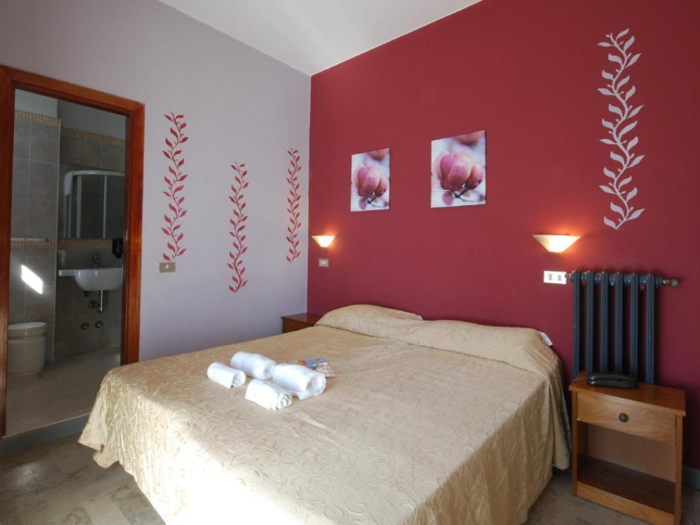 Camera con letto matrimoniale, bagno privato e decorazioni floreali sulle pareti.