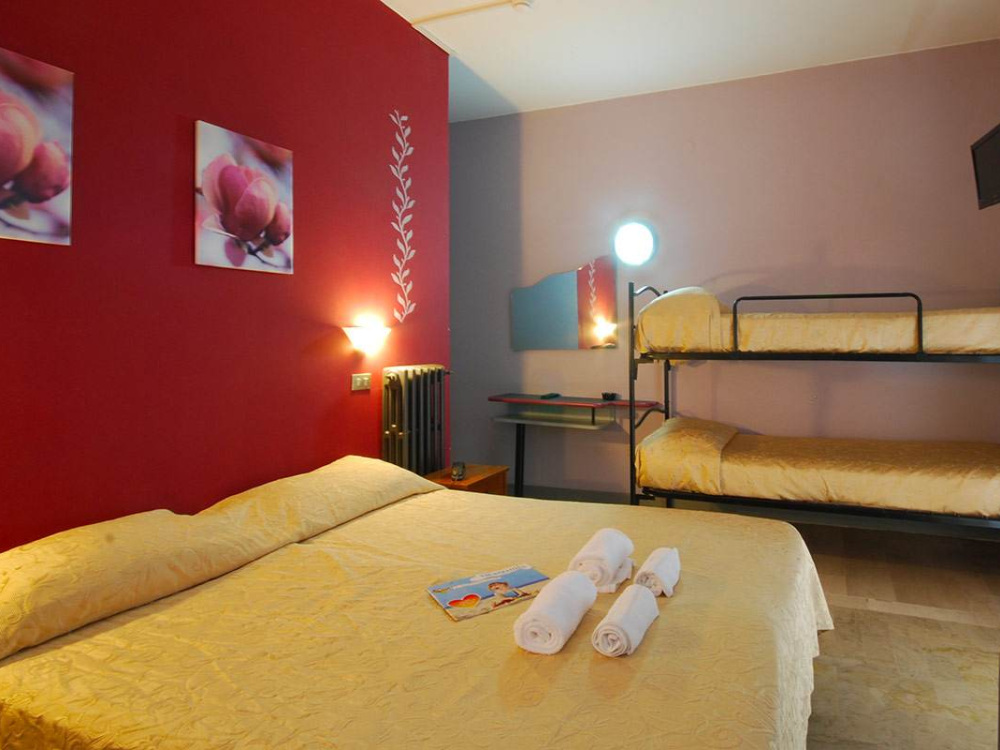 Camera con letto matrimoniale, letti a castello, parete rossa e decorazioni floreali.