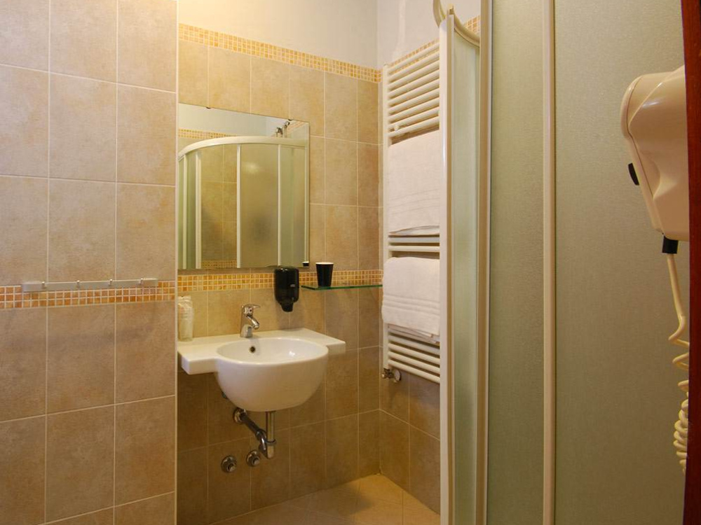 Bagno moderno con lavabo, doccia, specchio e asciugamani su scaldasalviette.