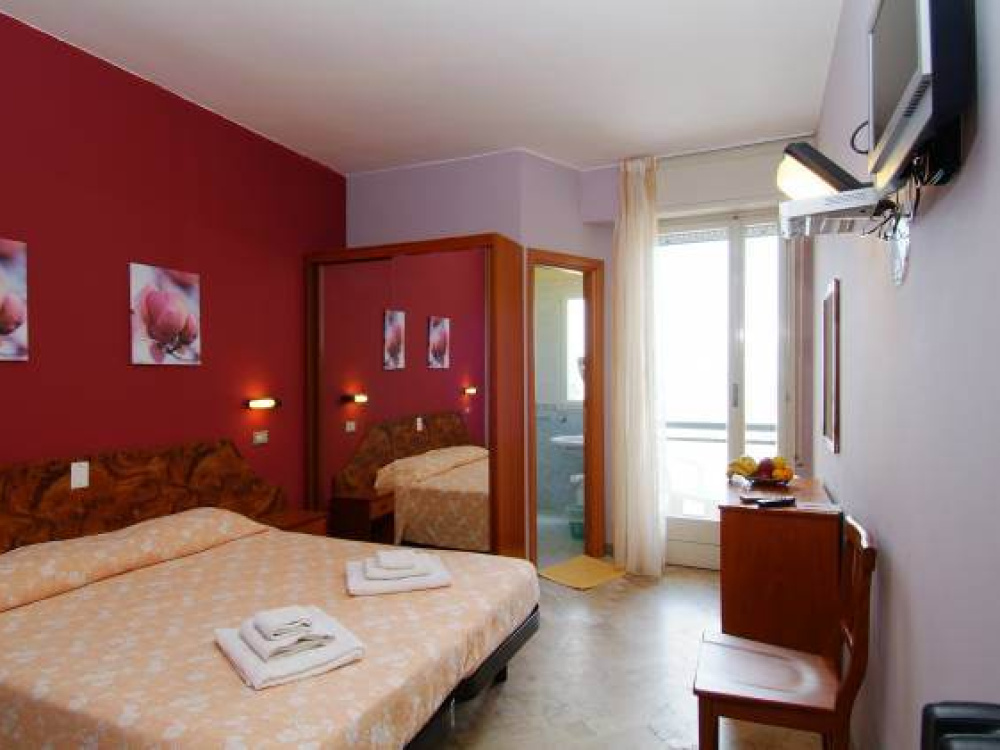 Camera d'albergo con letto matrimoniale, TV e balcone.