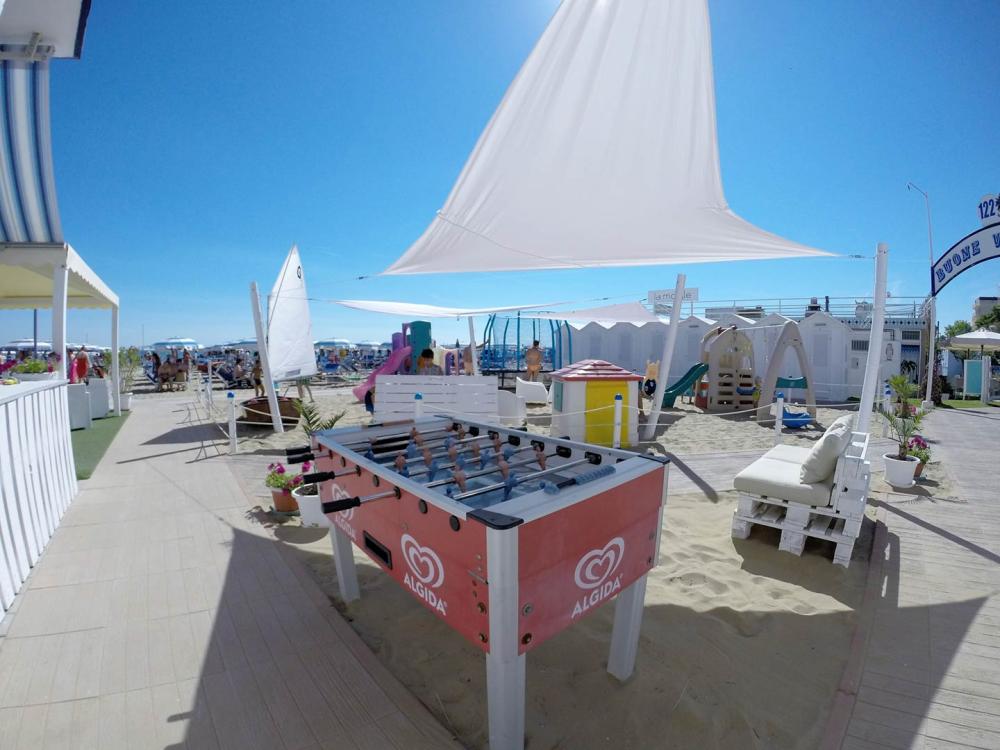 Spiaggia con calcio balilla, giochi per bambini e ombrelloni.